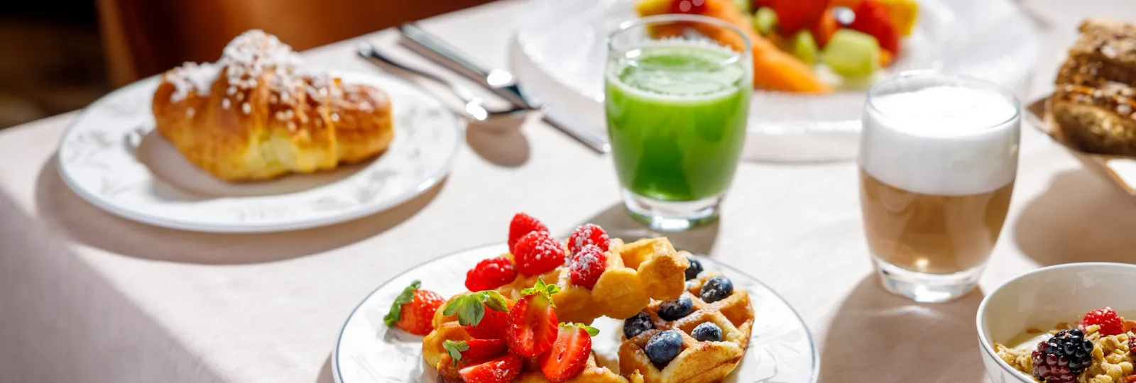 Acanto breakfast with waffles, a cappuccino and a green smoothie