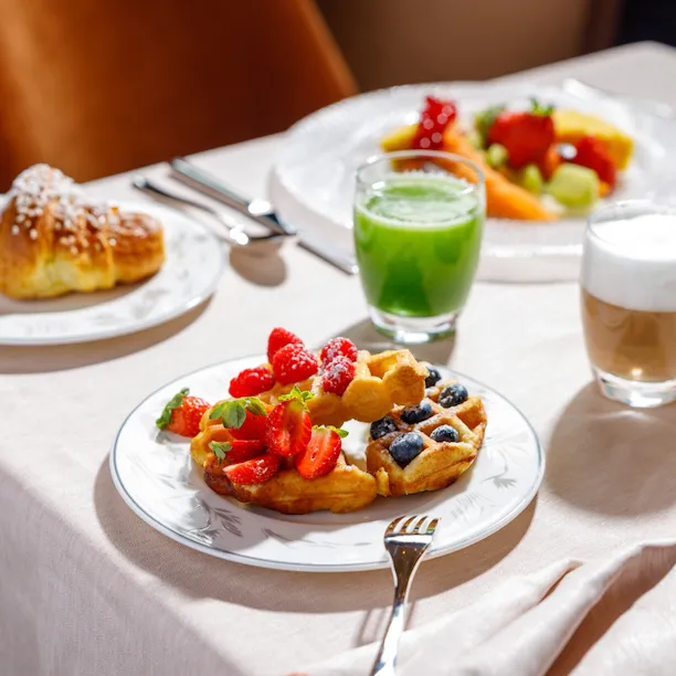 Acanto breakfast with waffles, a cappuccino and a green smoothie