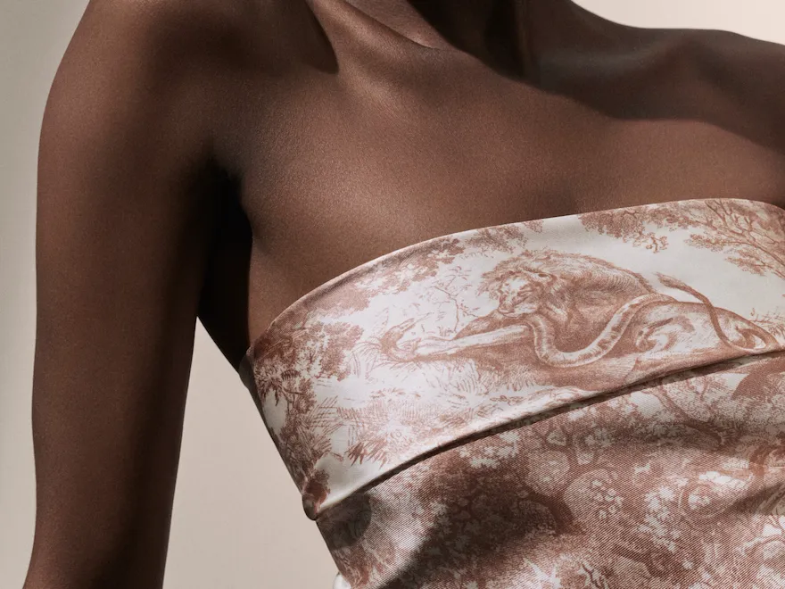 Dior Spa Plaza Athénée's iconography for spa treatments. Here, a dark-skin female model posing on her right shoulder, dressed in a silky white and pink Dior top.