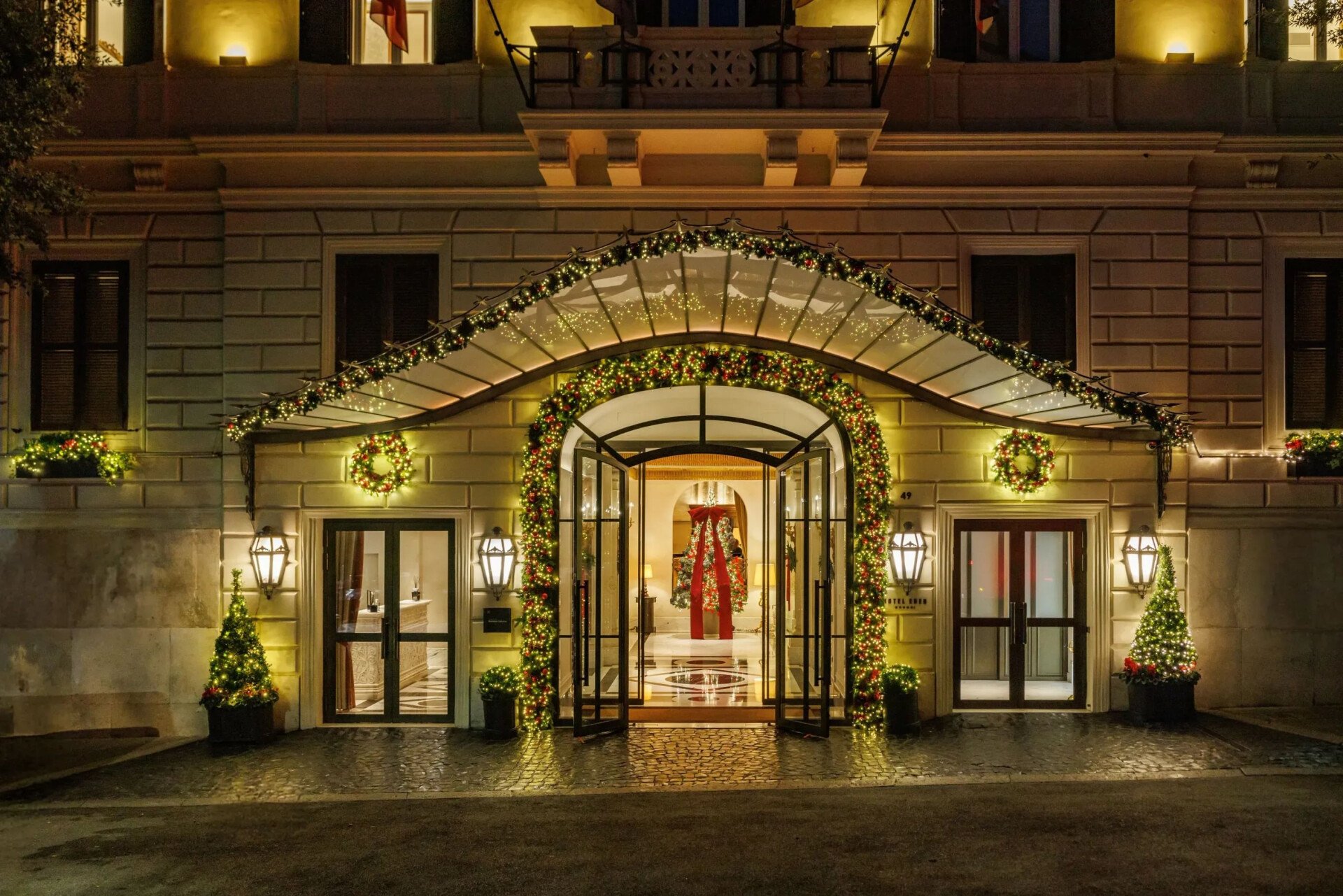 Hotel Eden main entrance at night decked with christmas decorations and lights with Christmas tree framed by main door