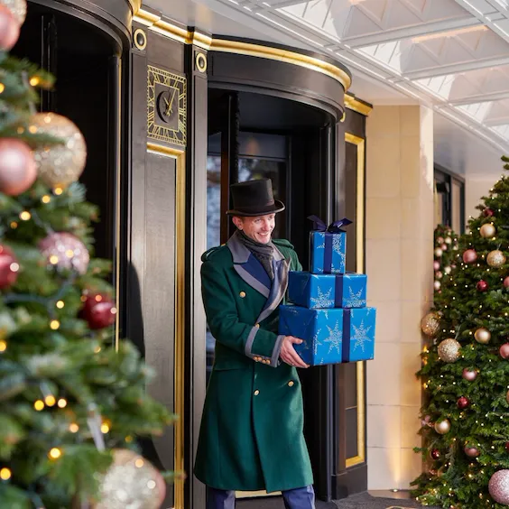 The Dorchester Doorman carrying a Christmas Present