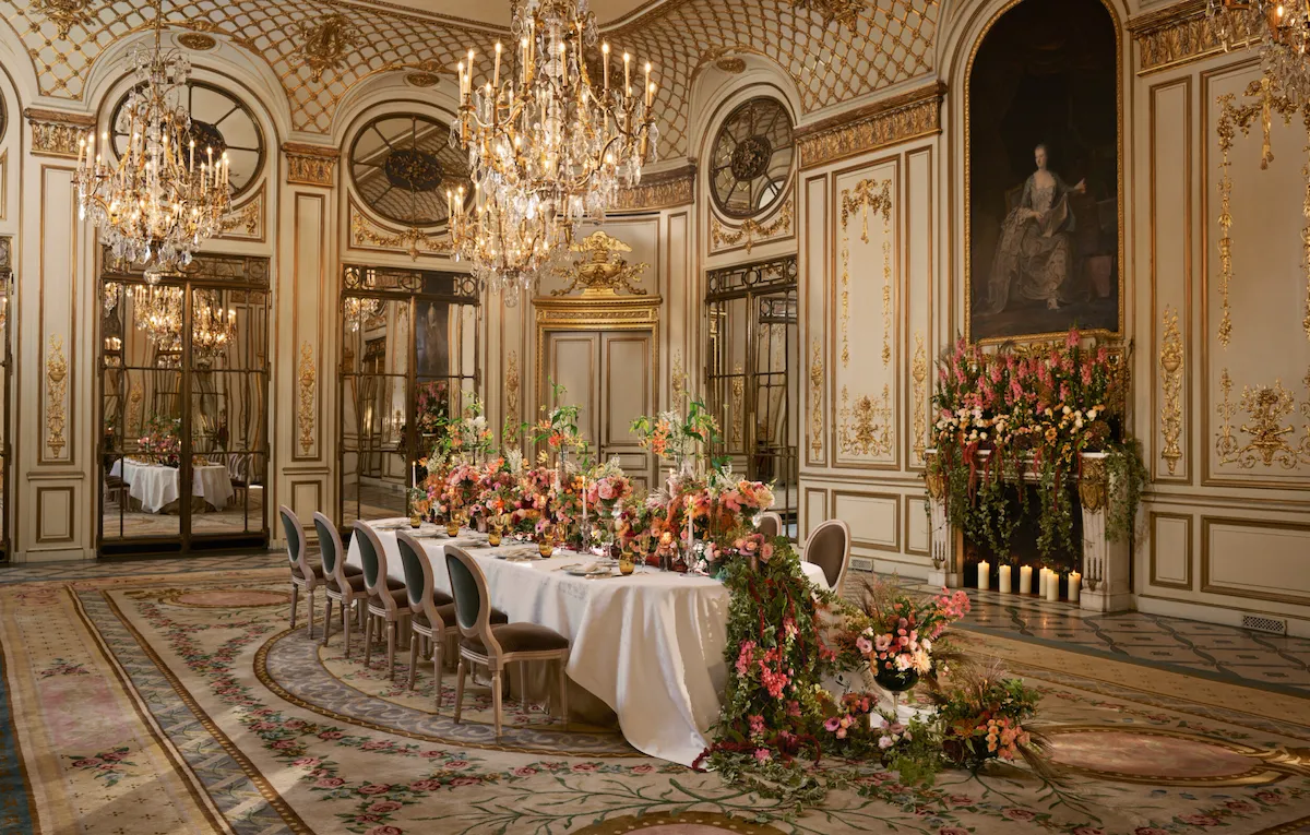 Private dinner at Le Salon Pompadour with long floral arrangement and fireplace in the background at Le Meurice, Paris - Dorchester Collection.
