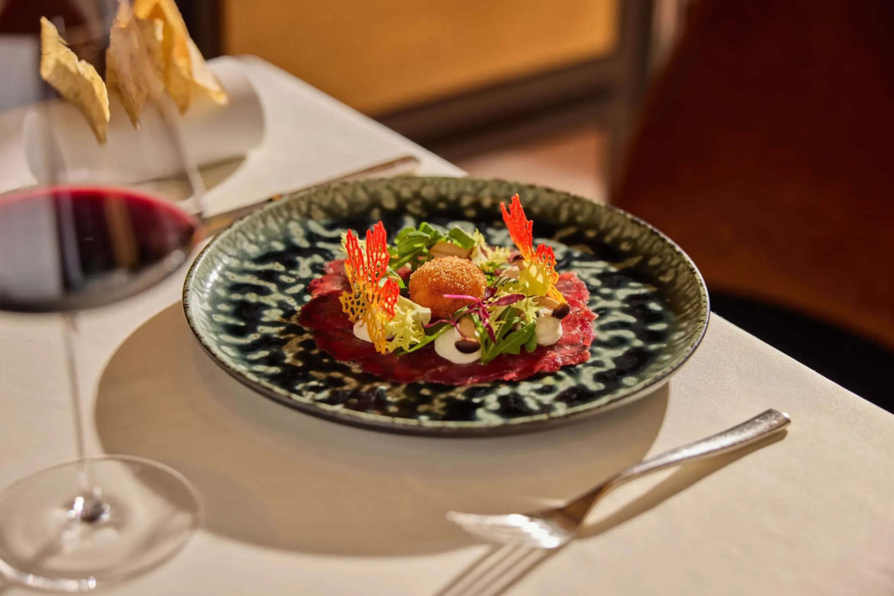 Juniper infused beef carpaccio, pioppini mushrooms, potatoes, crispy egg yolk and Parmesan cream