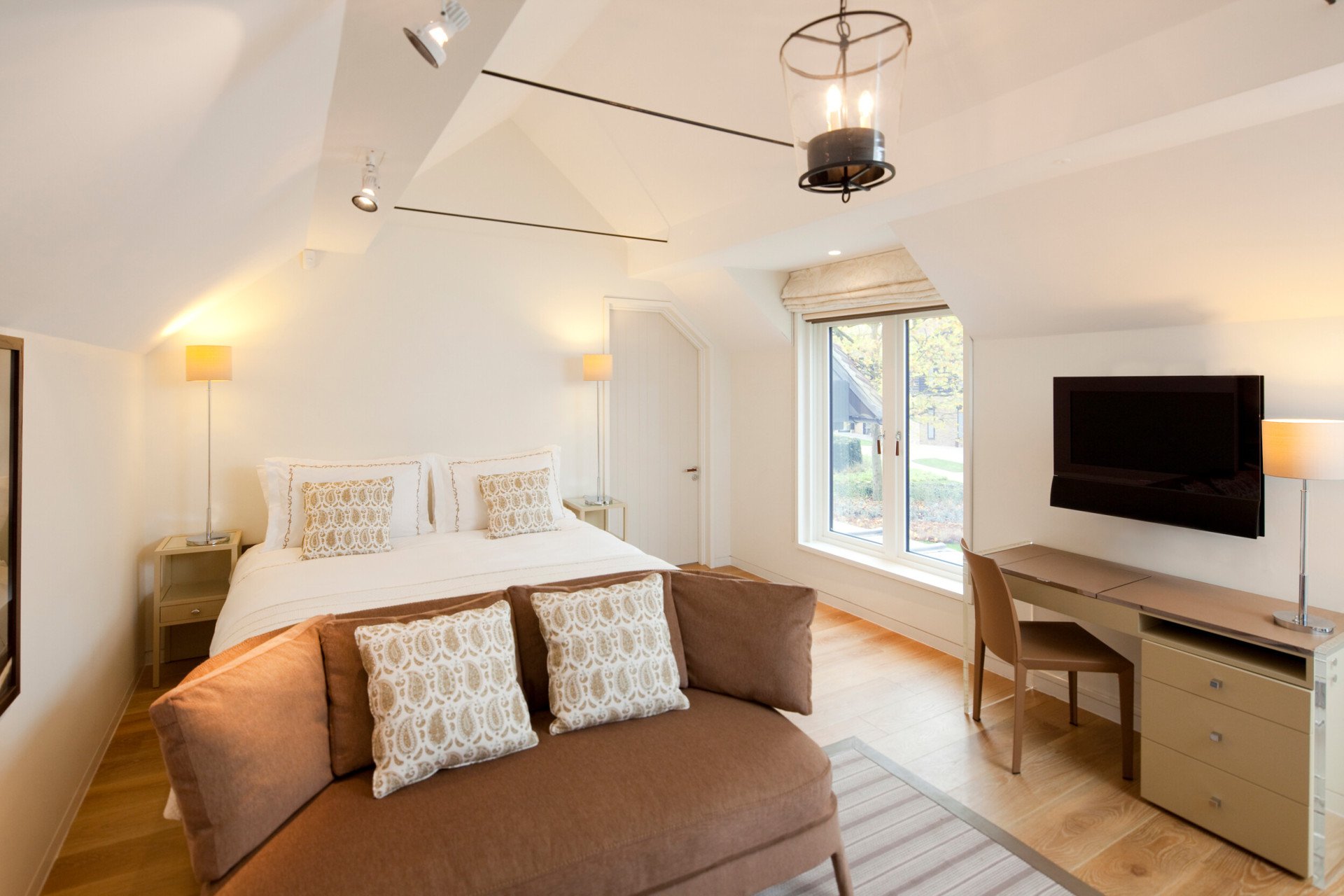 Stable deluxe bedroom interiors with bed, sofa nd television at Coworth Park 