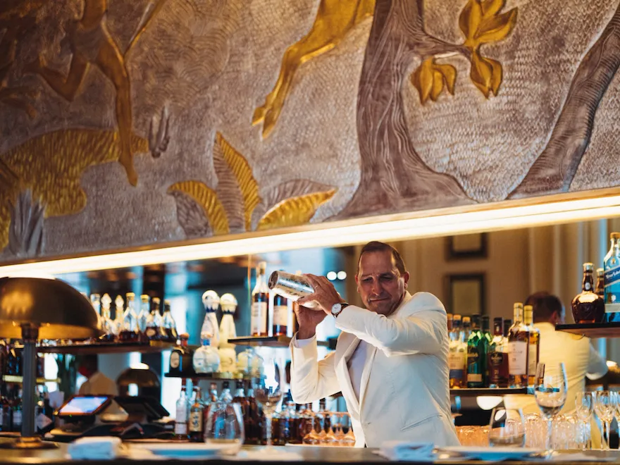 Le Relais Plaza bartender shaking a cocktail at the bar, at Hotel Plaza Athénée, Paris
