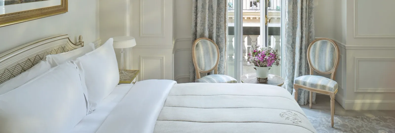 View from the right with the bed next to the flowers in front of the window, at Le Meurice, Paris