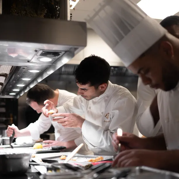 It is a photo of chefs very focused on the dressage of their plates in the kitchen, at Le Meurice, Paris.