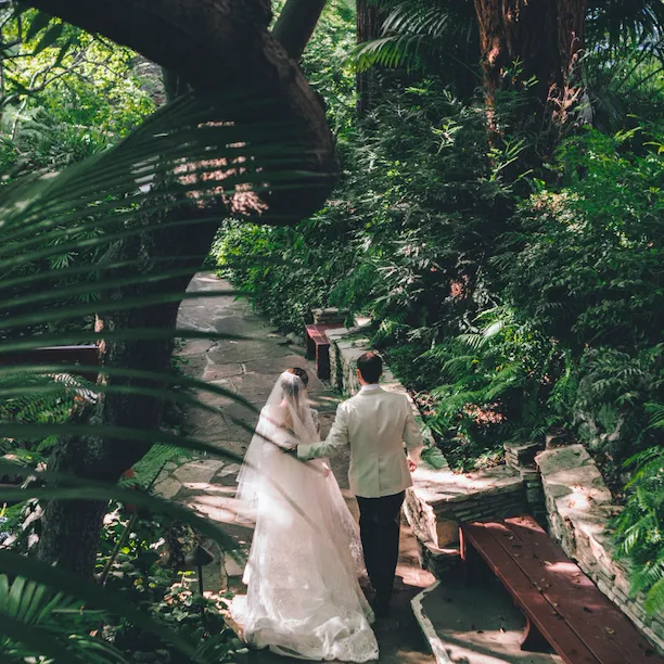 The happy couple walking hand in hand in the gardens of Hotel Bel-Air