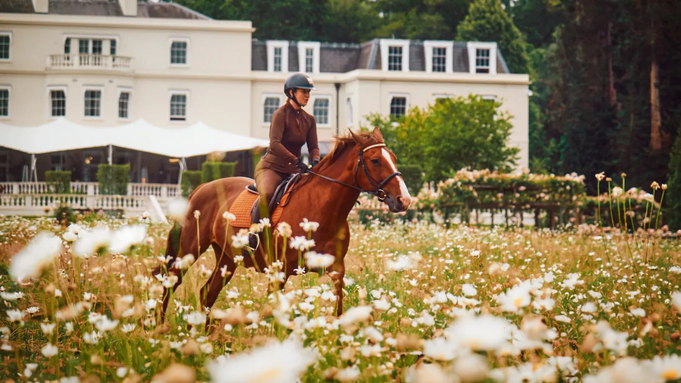 Horse riding through the meadow in front of the mansion house
