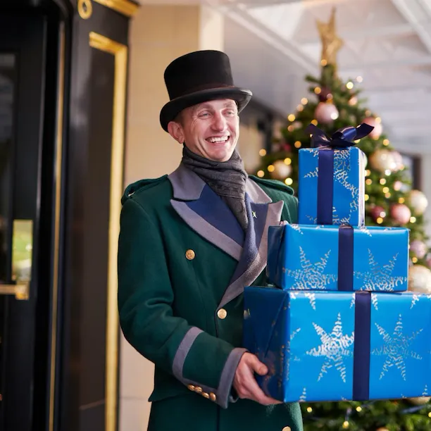The Dorchester Doorman carrying a Christmas Present