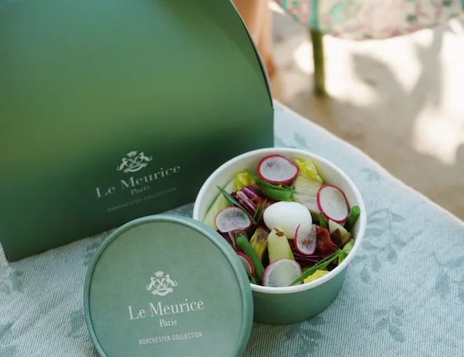 Le Meurice lunchbox, a bun and a salad displayed on a napkin.