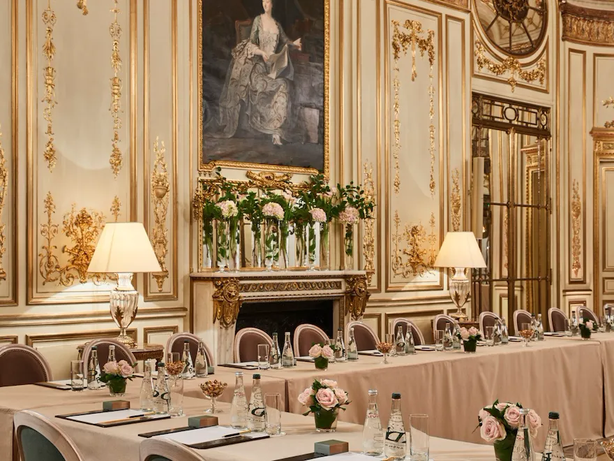 A Sala Pompadour foi transformada em uma sala de reuniões em forma de U. Nas mesas temos flores, papéis, canetas e garrafas de água, no Meurice, em Paris.
