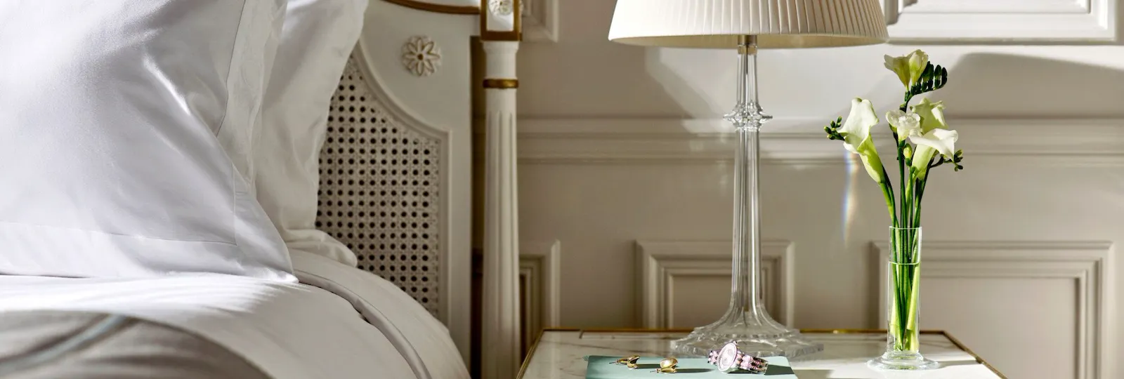 A few pieces of jewelery and a watch placed on the bed side table of a superior room. At Le Meurice, Paris.