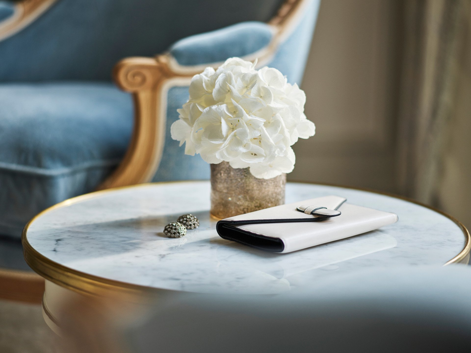 A wallet, flowers and earrings on a low table in a deluxe suite at Le Meurice, Paris.