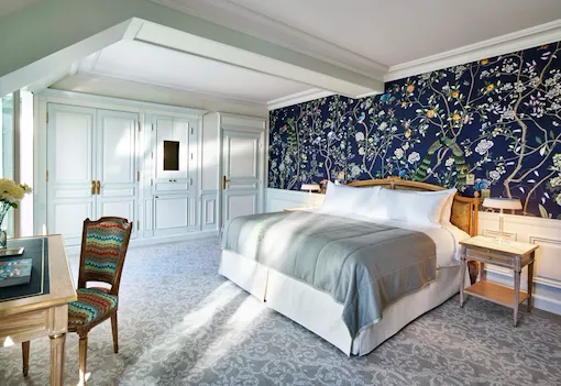 Overview of an executive room with balcony highlighting the dark blue hand painted wall with nature details. At Le Meurice, Paris.