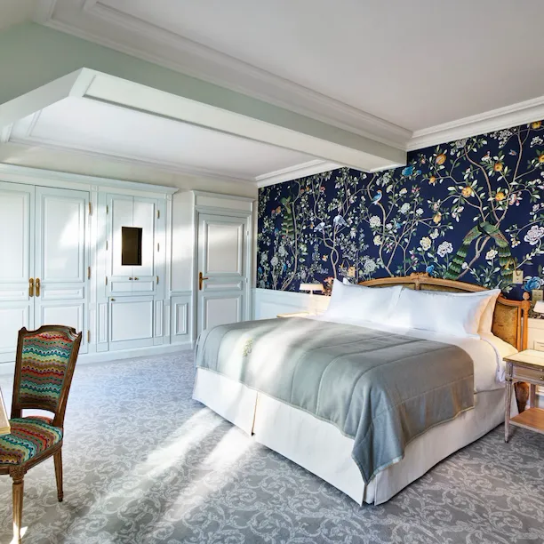 Overview of an executive room with balcony highlighting the dark blue hand painted wall with nature details. At Le Meurice, Paris.