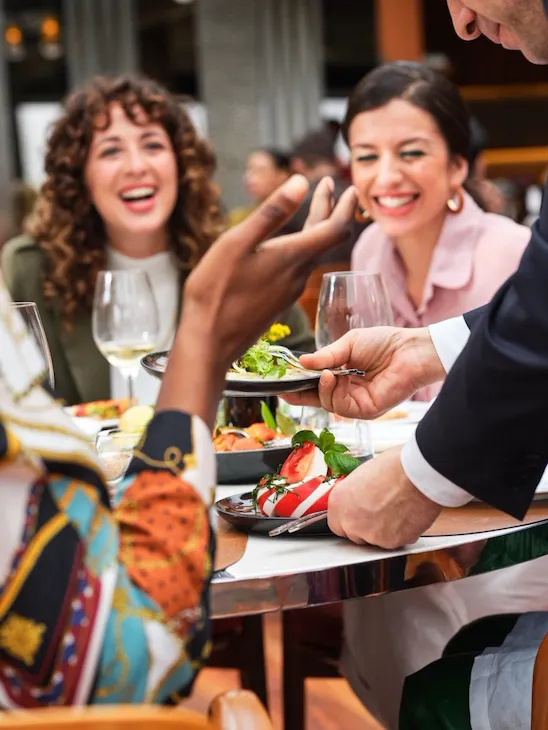 Primo piano sul tavolo composto da amici che brindano al ristorante Il Giardino, Hotel Eden