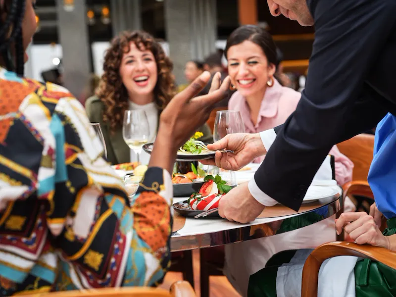 Primo piano sul tavolo composto da amici che brindano al ristorante Il Giardino, Hotel Eden