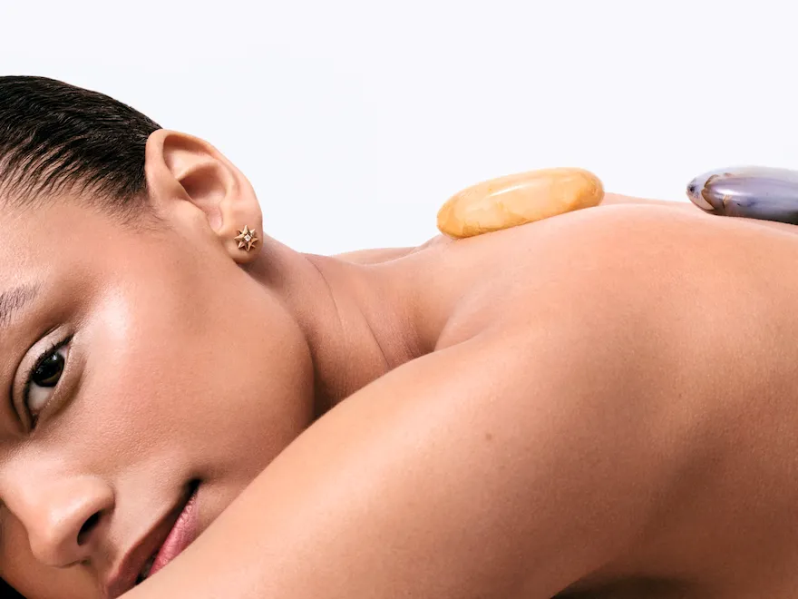 A woman is laying, stone on her back