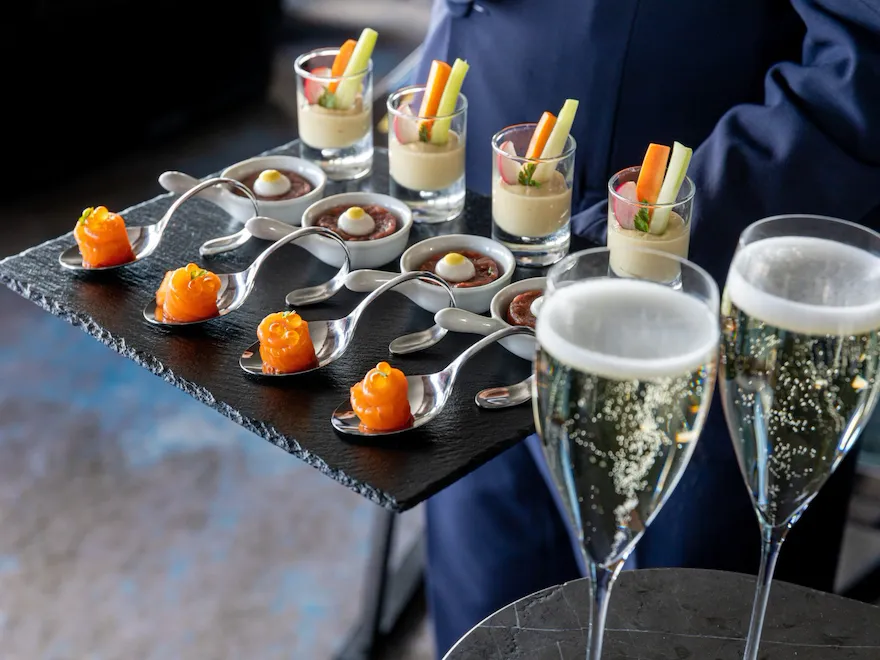 Selection of finger food on slate tray and two glasses of champagne at Hotel Eden, Rome