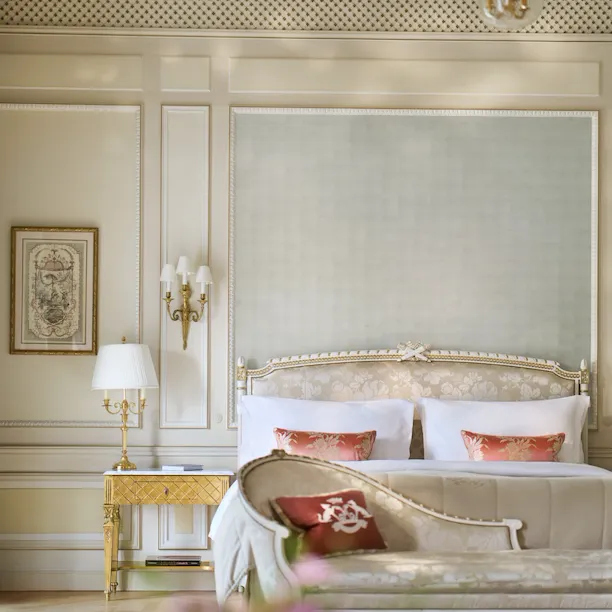 Vue de face de la chambre d’une suite Versailles avec le lit derrière le canapé, au Meurice, Paris