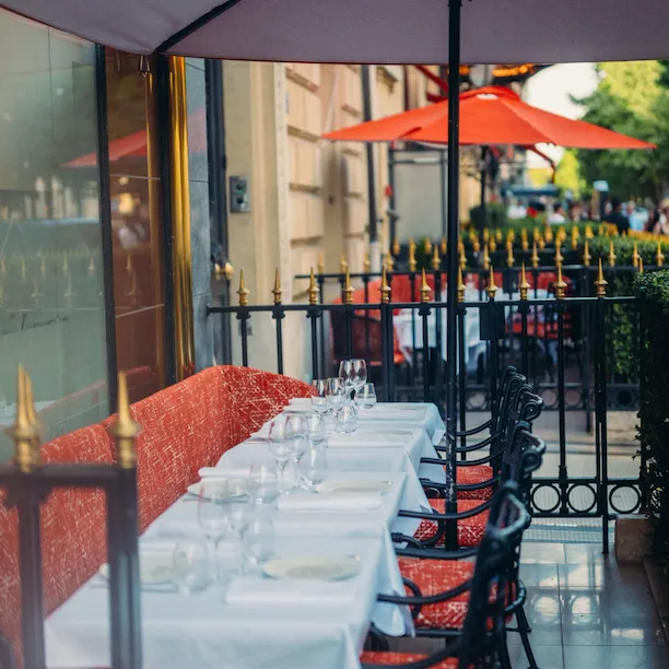 Relais Plaza's terrace with drawned up dining tables and Plaza red parasols, at Hotel Plaza Athénée, Paris