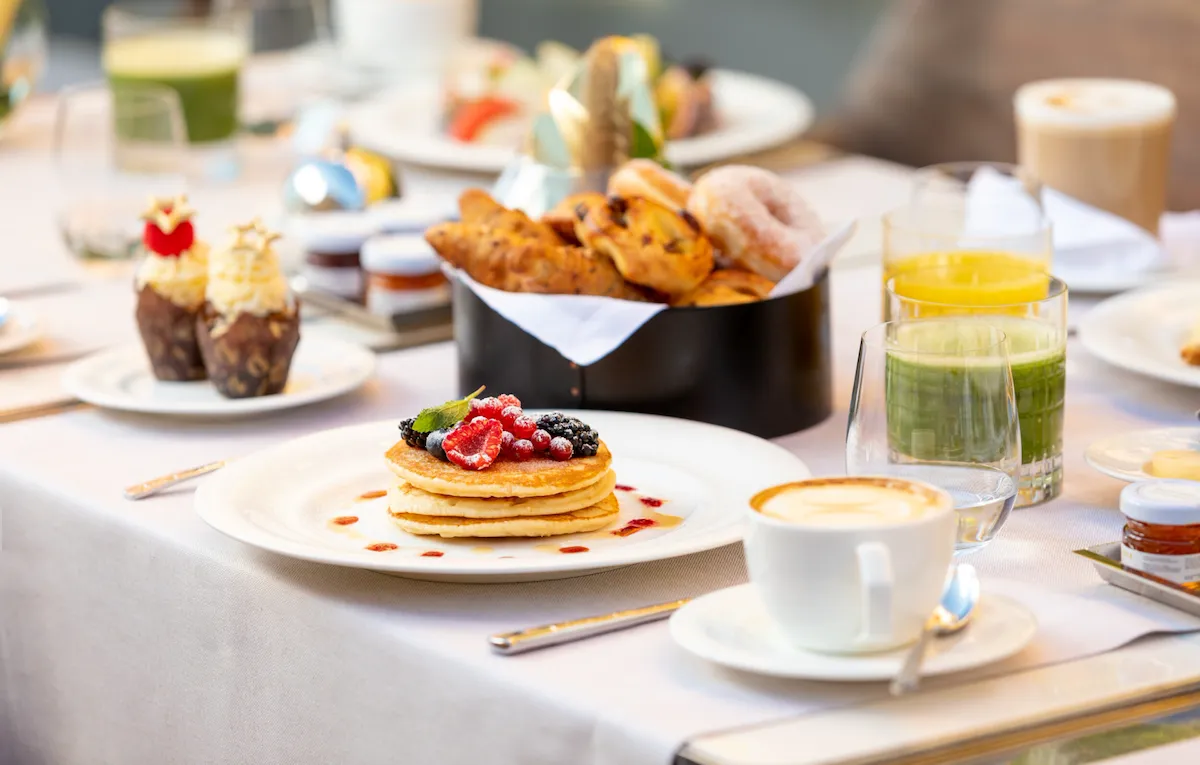 Tavolo de Il Giardino Ristorante apparecchiato per la colazione con tazza di cappuccino, piatto di pancake, cupcakes, selezione di cornetti