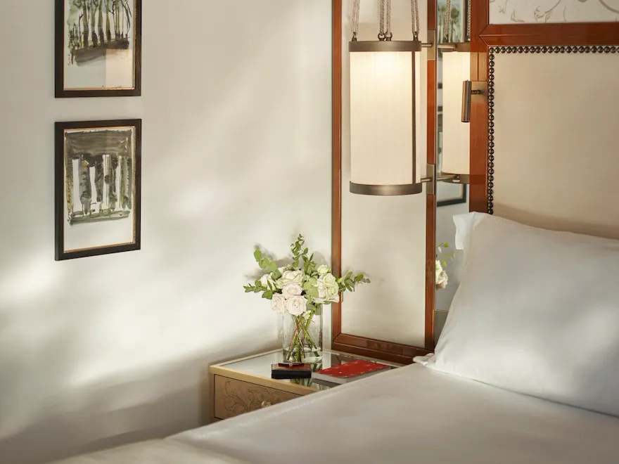 Bedroom detail of Prestige Suite with bouquet of flowers on night table at Hotel Eden, Rome