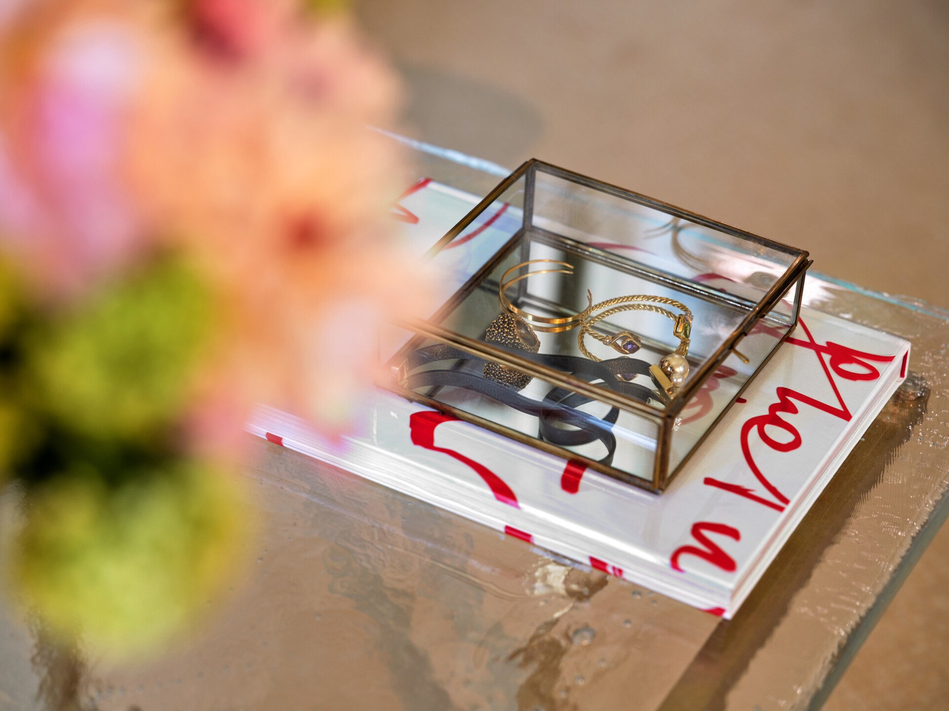 Libro e portagioie trasparente contenente alcuni gioielli su di un tavolo da salotto in una suite di Hotel Eden Roma