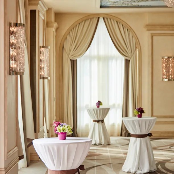 tre tavoli da cocktail in sala veranda con centrotavola di fiori rosa e verdi