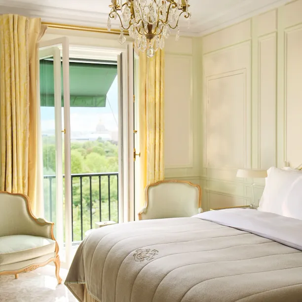 Bedroom in soft beige colours, two single sofas in light green are placed next to the window with yellow curtains, at Le Meurice, Paris