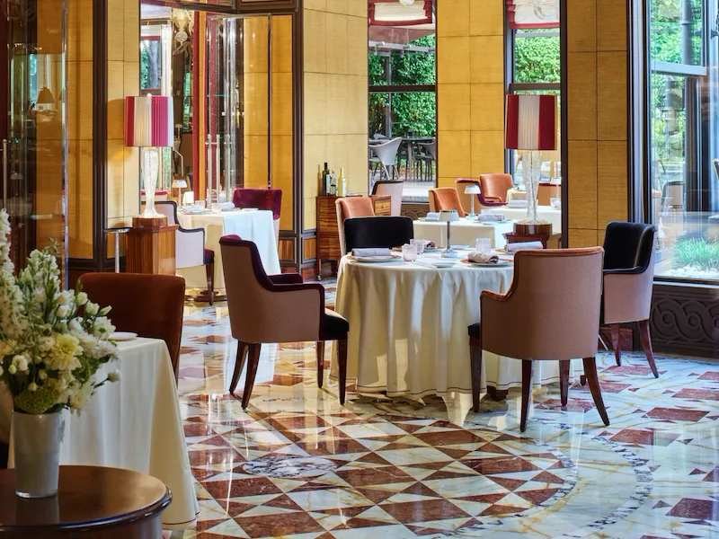 Acanto restaurant interior. Tables, chairs and garden in the background