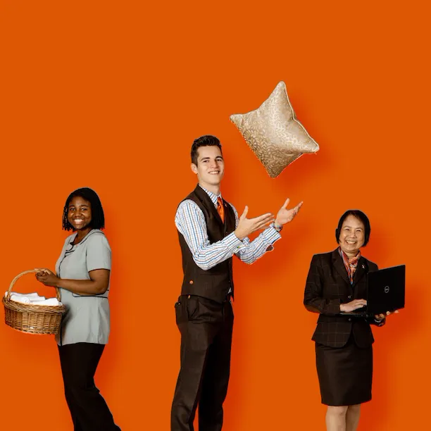 Group of people holding various items used by the rooms division at a hotel
