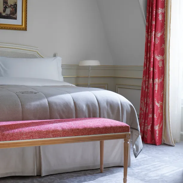 Gros plan du lit et du banc devant dans la chambre d'une suite junior exécutive au Meurice, Paris.