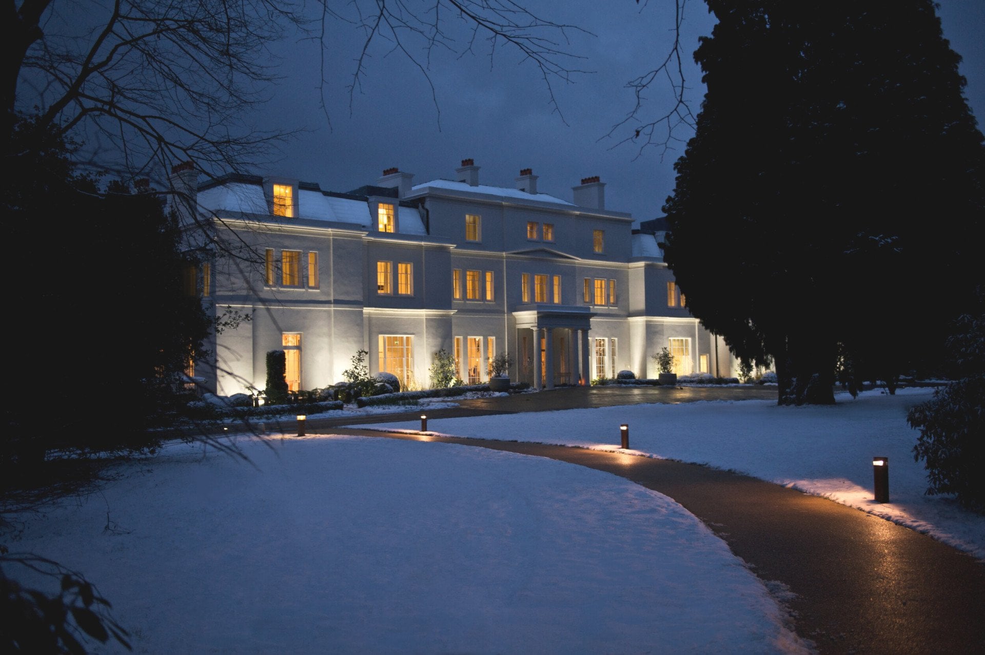 Mansion House exterior at night with snow covered grounds at Coworth Park, Ascot