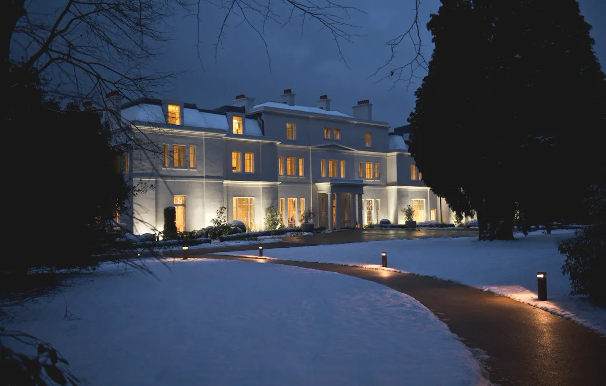 Mansion House exterior at night with snow covered grounds at Coworth Park, Ascot