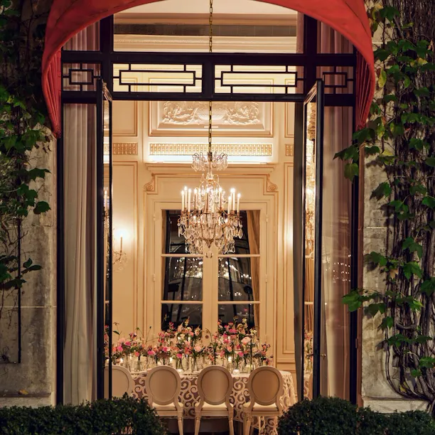 Table captured from outside with colorful flower arrangement at Le Salon Organza, Hôtel Plaza Athénée, Paris - Dorchester Collection.