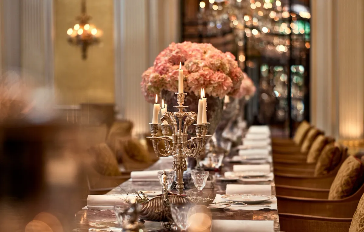 Jean Imbert au Plaza Athénée's central marble table, drawned up with pink flowers and candleholders. At Hotel Plaza Athénée, Paris