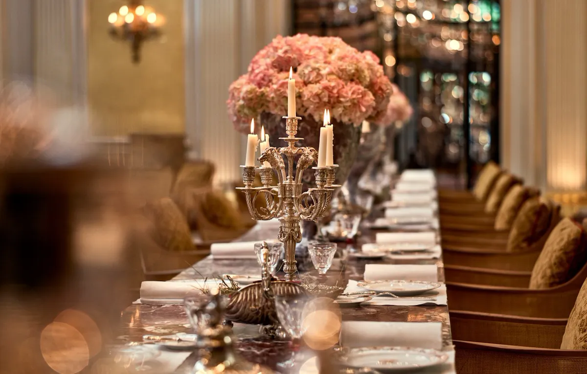 Jean Imbert au Plaza Athénée's central marble table, drawned up with pink flowers and candleholders. At Hotel Plaza Athénée, Paris