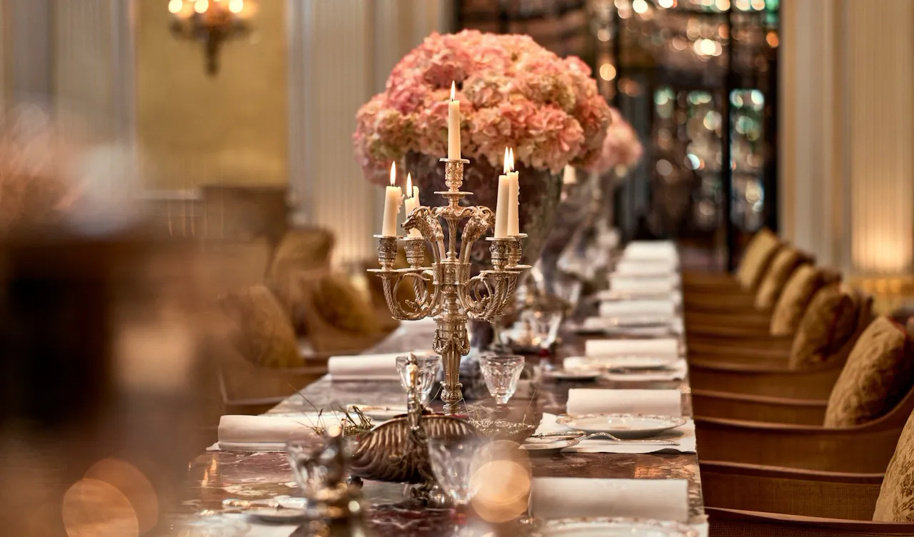 Jean Imbert au Plaza Athénée's central marble table, drawned up with pink flowers and candleholders. At Hotel Plaza Athénée, Paris