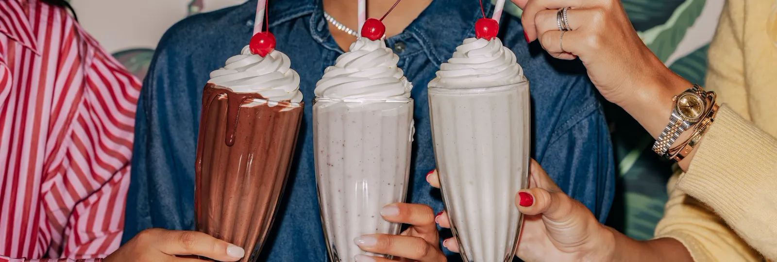 People enjoying milkshakes at a table, celebrating together with smiles and colorful surroundings