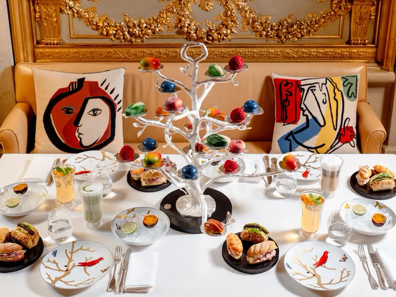 Elegant dining table with colorful cake, drinks, and a decorated white tree centerpiece.