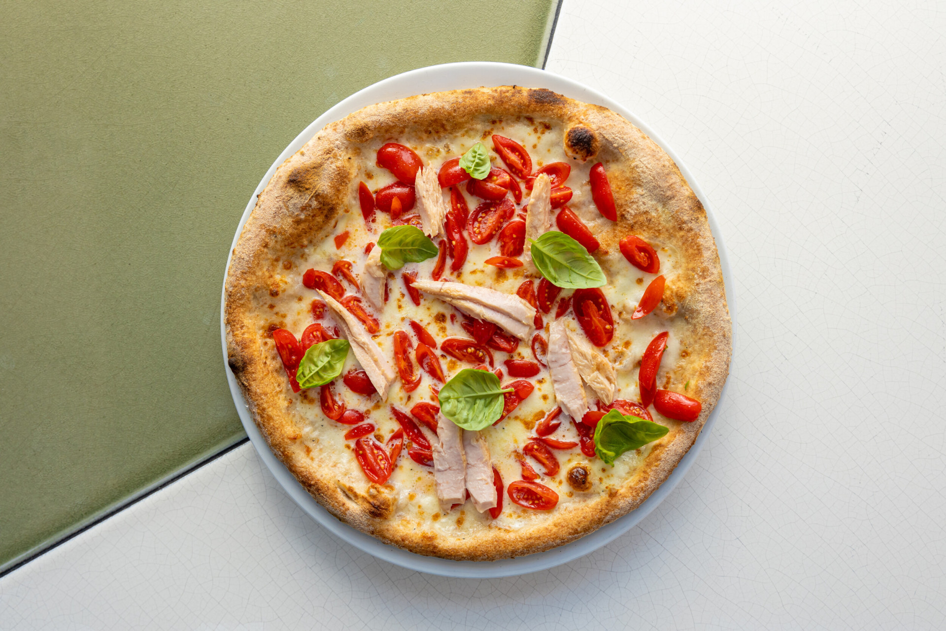 Pizza con pomodorini, mozzarella, tonno e basilico su di un tavolo de Il Giardino Ristorante a Hotel Eden Roma