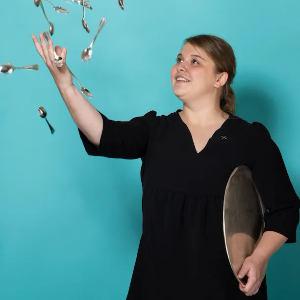 Woman throwing spoons against a blue background