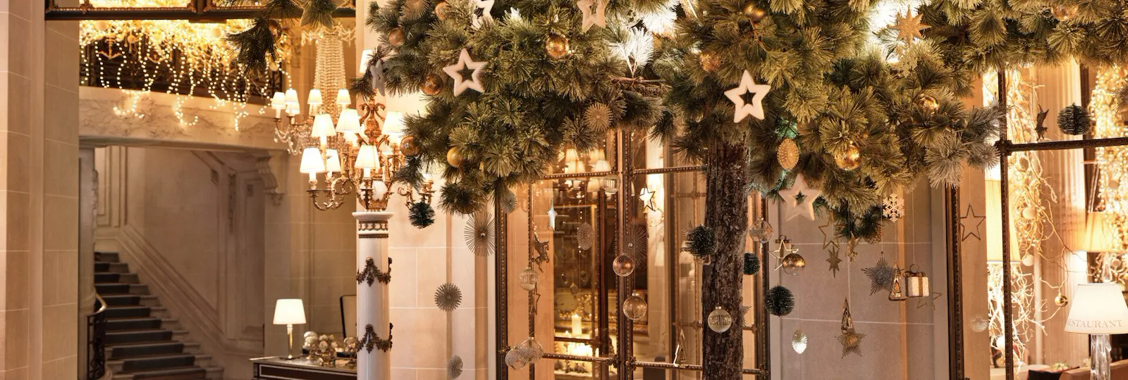 Large Christmas tree in the lobby, with decorations hooked on it and Christmas lights in the background at Le Meurice, Paris