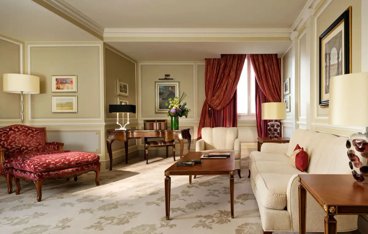 Principe Suite living room with red elements and a bouquet of flowers on the desk in the background