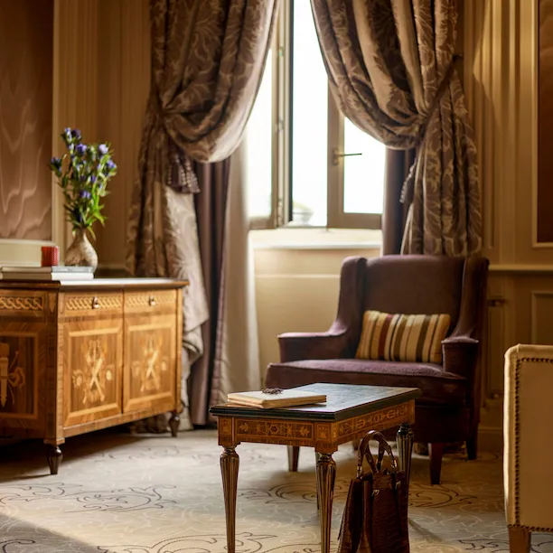 Soggiorno della suite Ambassador, particolare di una borsa marrone sul pavimento che si abbina ai colori dei mobili.