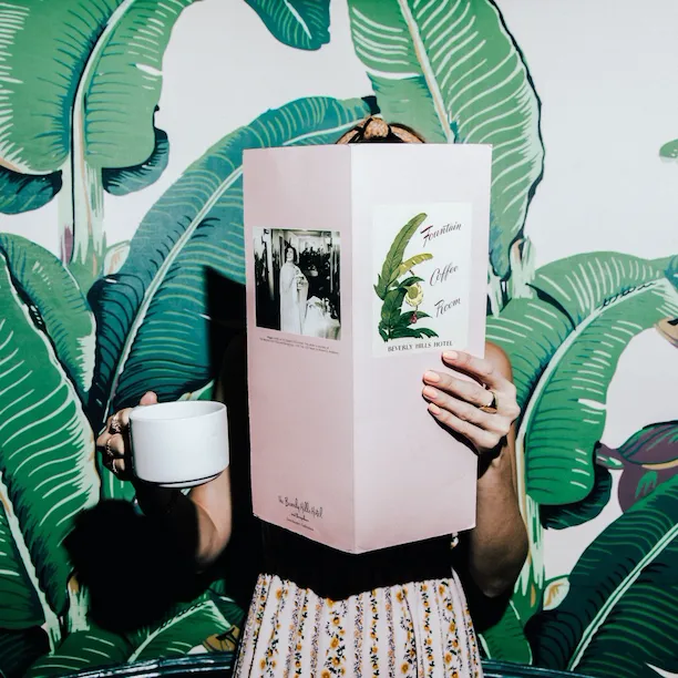 Woman reading menu and drinking coffee in The Fountain Coffee Room