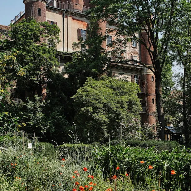 View of the Brera Observatory from the Orto Botanico in Palazzo di Brera with greenery and red flowers in the foreground