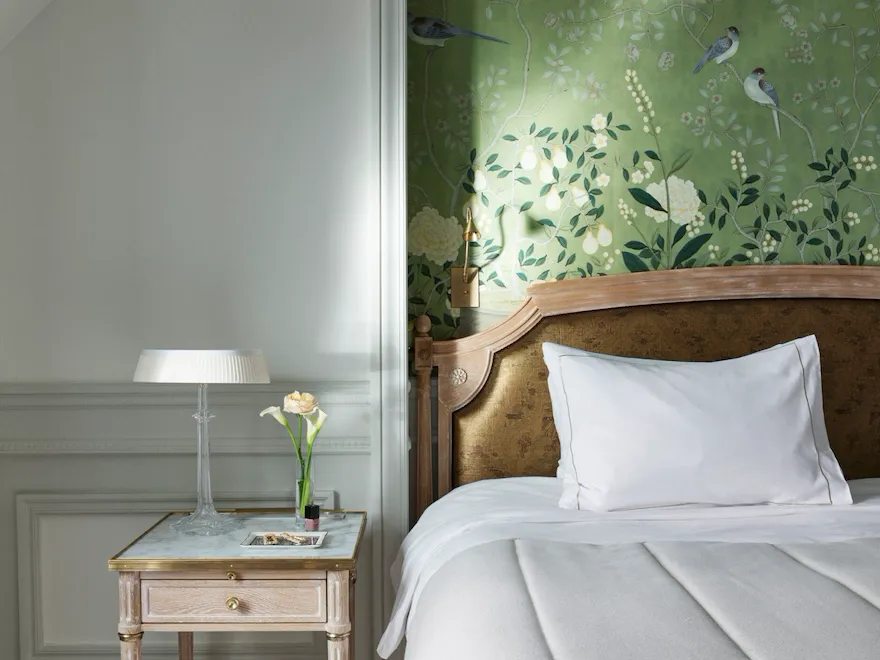 Portrait shot of an executive room with a green hand painted wall, and a wooden side table with a marble top. At Le Meurice, Paris.